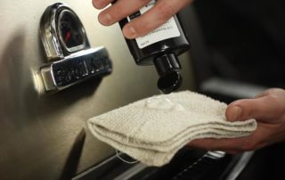 A person is applying cleaning fluid to a rag in preparation for cleaning a grill.